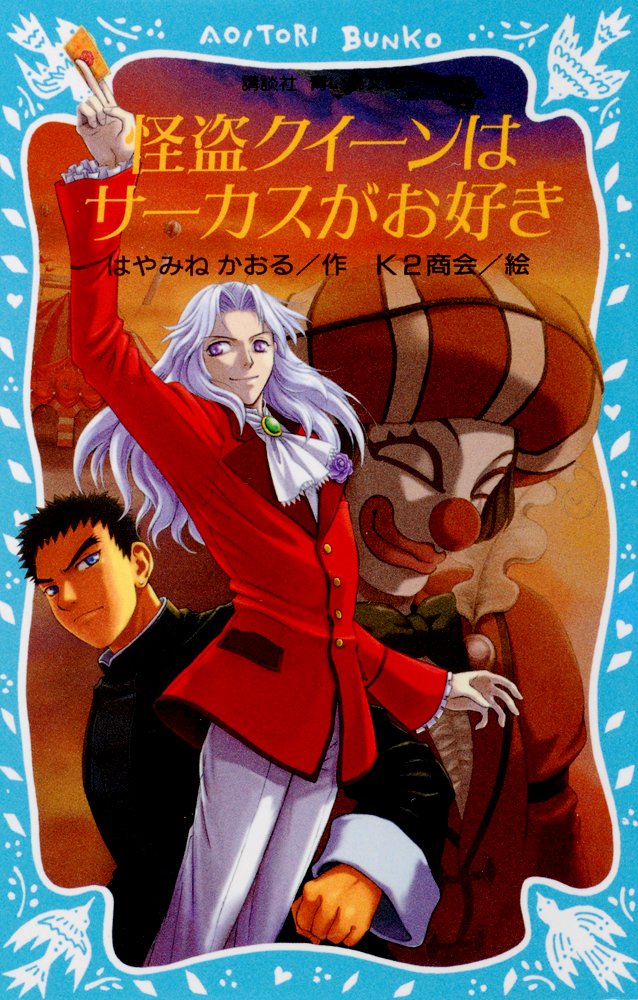 The cover of the first Kaitou Queen wa Circus ga Tsuki novel written by Kaoru Hayamine and published in Japan by Kodansha. The cover features an Asian man in a martial arts uniform, an androgynous person dressed in noble's clothing flourishing a playing card, and a sinister looking masked harlequin.