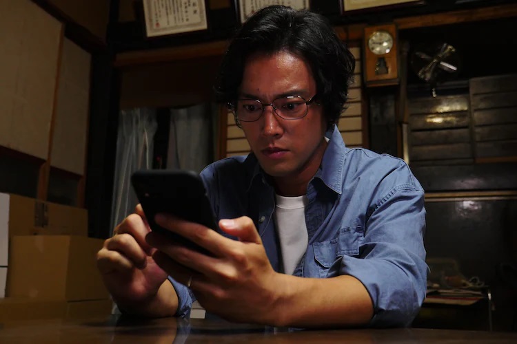 The character of Kenichi Nakaoka (played by actor Kenta Kiritani) consults a haunted password for the Dragon Quest II video game in a scene from the upcoming "Fukkatsu no Jumon" segment of the Tales of the Unusual TV drama.