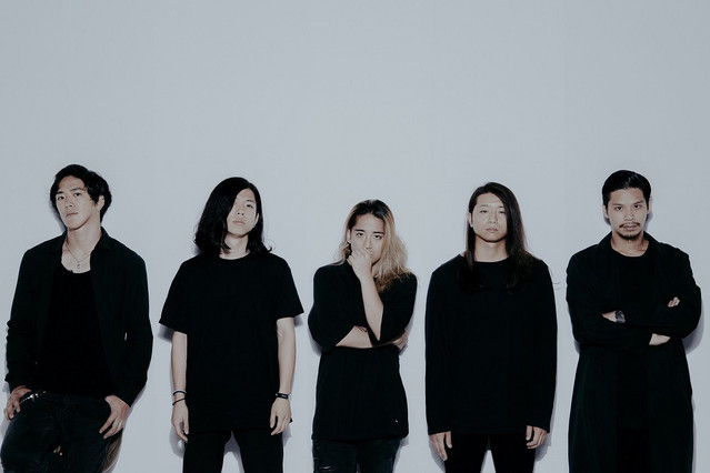 The five members of Survive Said the Prophet stand in a line against a white backdrop.