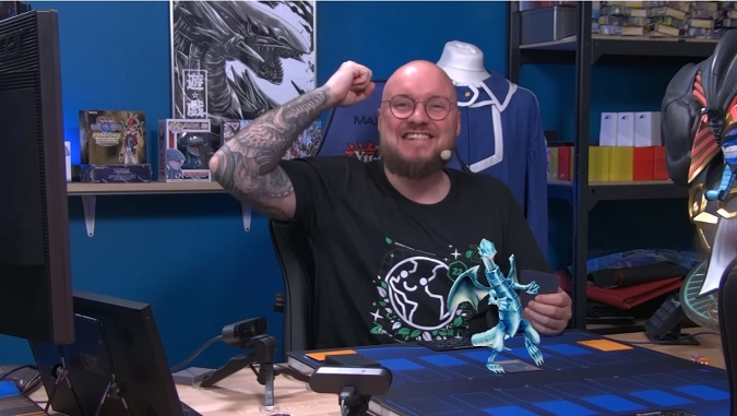 A screen capture of French streamer SuperZouloux demonstrating his augmented reality Yu-Gi-Oh! play mat, which displays a 3DCG model of a Blue Eyes White Dragon that he summons.