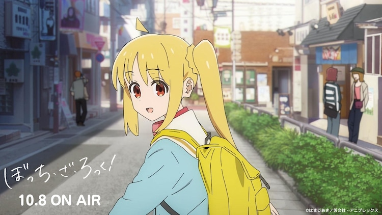 While strolling down a pleasant shopping street wearing her school uniform and backpack, Nijika Ijichi turns and smiles at her friends in a scene from the upcoming Bochii the Rock! TV anime.