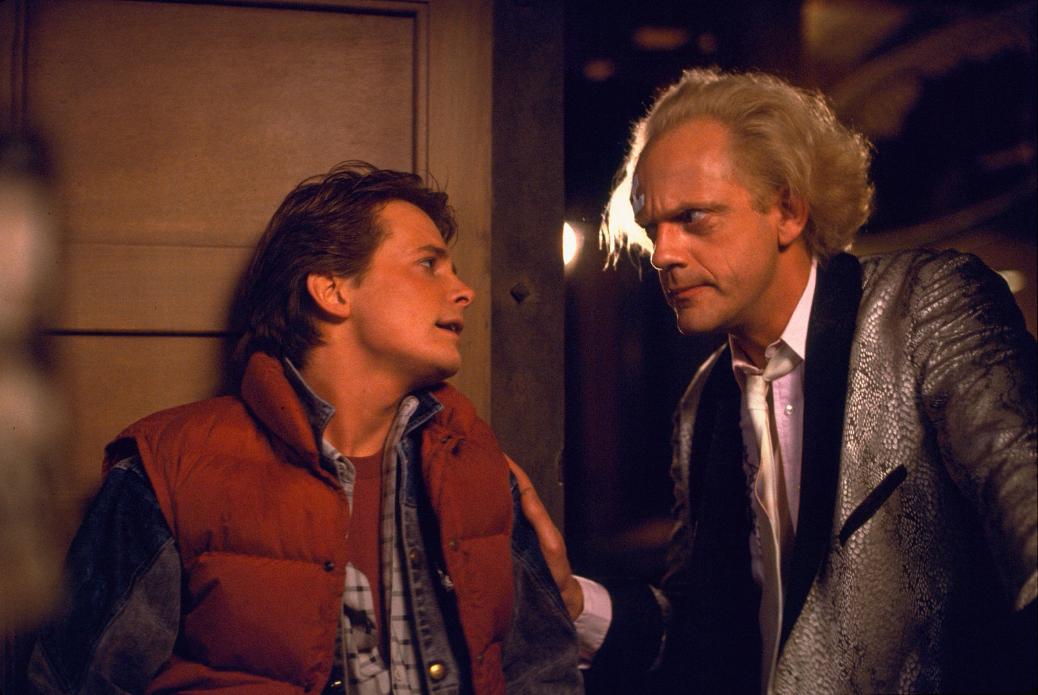 Die Schauspieler Michael J. Fox und Christopher Llyod interagieren mit ihren Charakteren Marty McFly und Doc Brown in einer Szene aus dem Film Zurück in die Zukunft von 1985.