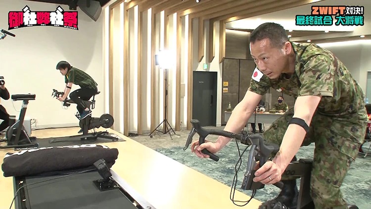 A worker for Yamato Transport and a soldier for the JGSDF face off in a socially-distanced virtual cycling battle for the upcoming Onsha Heisha Matsuri Youtube program.