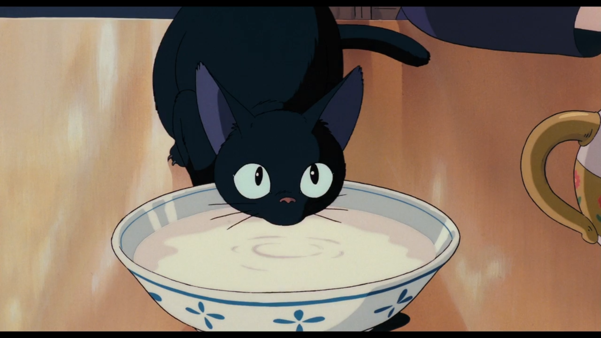 Jiji drinks from a bowl of milk in Kiki's Delivery Service