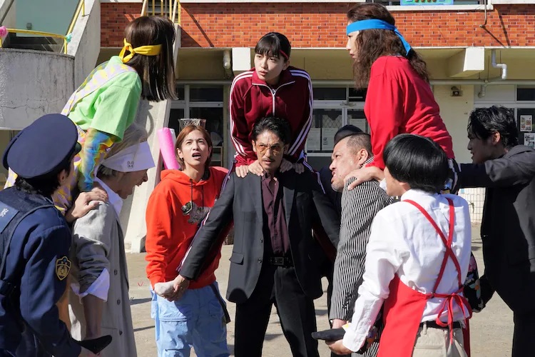Tatsu and his neighbors confront each other in a "cavalry battle" in a scene from the upcoming live-action The Way of the Househusband theatrical film.