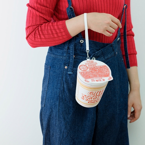 A model demonstrates how to carry the large-sized Cup Noodle pouch included as a limited edition pack in bonus with Takarajimasha's CUP NOODLE 50TH ANNIVERSARY BOOK.