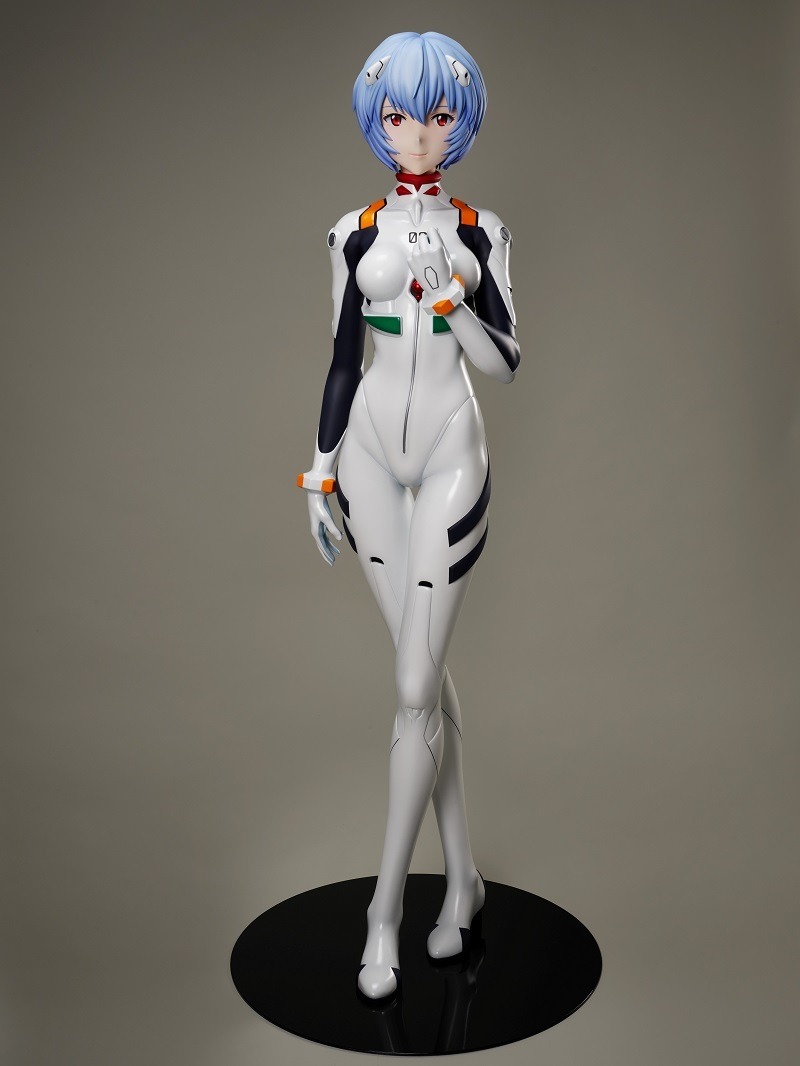 Ein Werbebild der 1: 1-Figur von Rei Ayanami aus F: NEX mit einer Weitwinkelaufnahme eines Prototyps der Figur, der sowohl seine Größe als auch den Sockel zeigt.