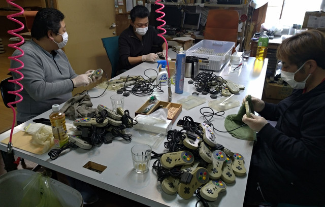 Members of the Japan Retro Game Association clean and sterlize Super Famicom controllers for a charitable giveaway.