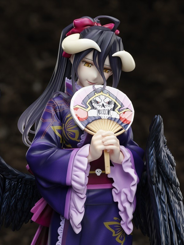 A promotional image of the Albedo 1/8 scale yukata figure, featuring the succubus Albedo dressed demurely in a summer kimono and clutching a paper fan emblazoned with a cartoon image of her beloved superior, the undead overlord lich Ainz Ooal Gown.