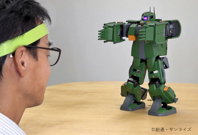 A researcher dons a XB-01 cerebral bloodflow sensor and operates a motorized, remote control Zaku toy by issuing it mental commands interpreted by a smart phone app as part of the ZEONIC TECHNICS Robotics and Programming Course I.