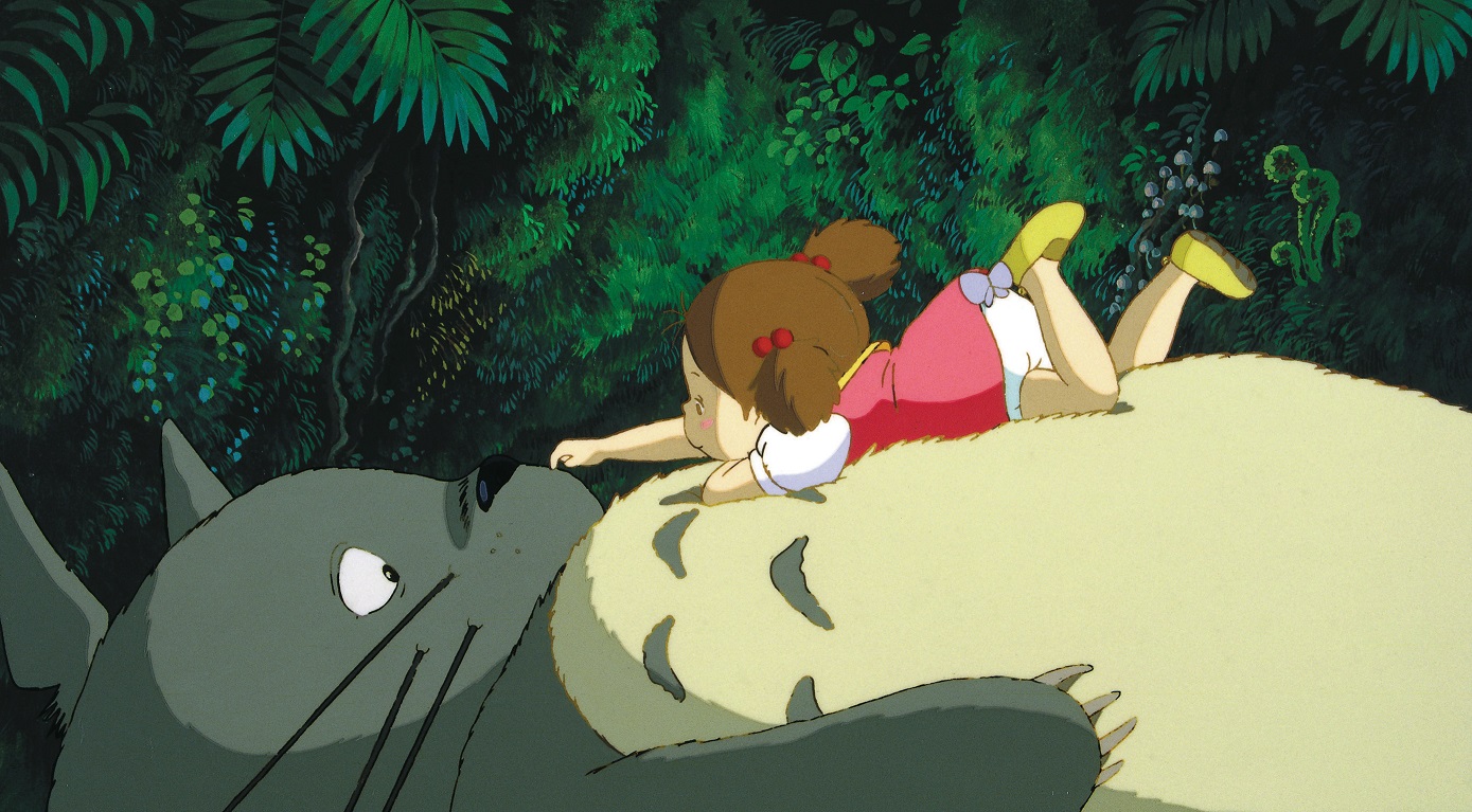 Mei gently tickles Totoro's nose while laying on top of the friendly, fuzzy forest spirit in a scene from the My Neighbor Totoro film.